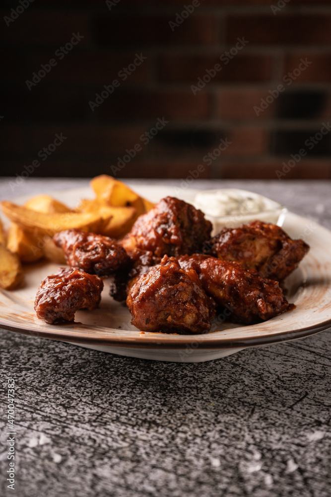 selective focus. barbecue chicken wings in breaded and sweet sauce. with natural sauce. restaurant serving. on a dark background. for menus and ads selective focus. barbecue chicken wings in breaded and sweet sauce. with natural sauce. restaurant serving. on a dark background. for menus and ads