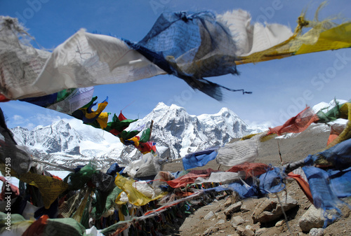 Prayer flags flutter on the backdrop of Mt. Khangchenghao (male) and Mt. Chomoyomo (female) look mesmerizing at Gurudongmar Lake situated at 17,800 ft altitude in North Sikkim, India. 