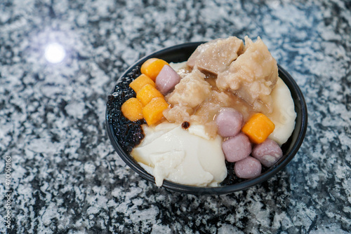 Taiwanese shaved ice with toppings. A Bowl of shaved ice with brown sugar syrup, topped with bubbles (black pearl), taro balls, taro and bean tofu. (isolated)
