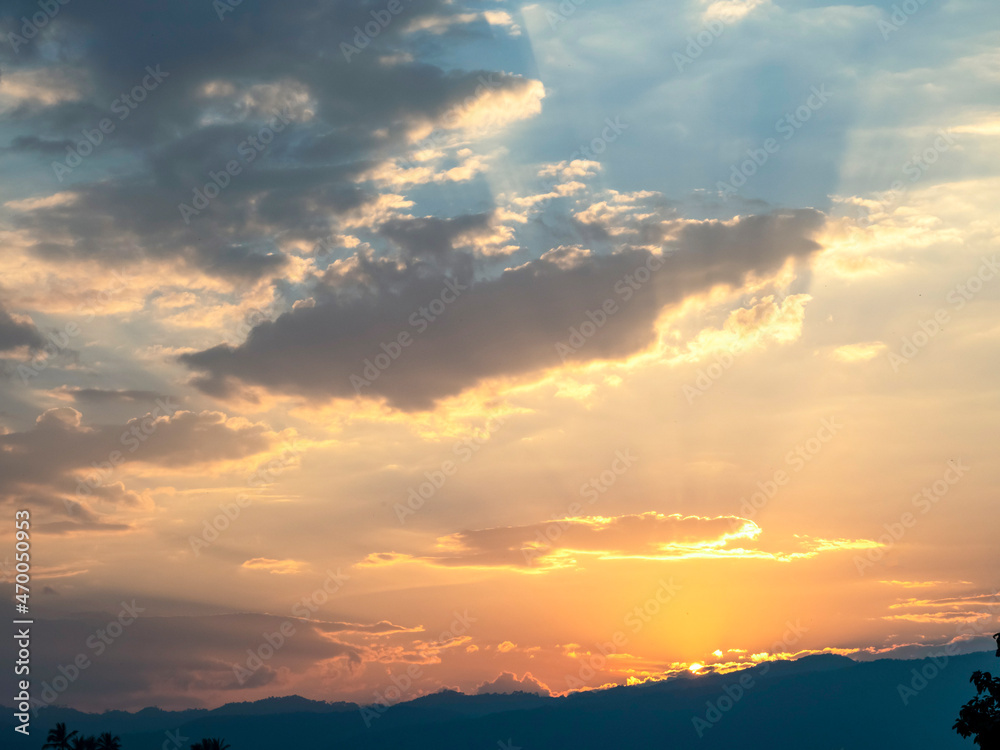 Fototapeta premium Beautiful sunset in the mountains. Landscape with sun shining through orange clouds, Sun setting over hills, sunset on mountains