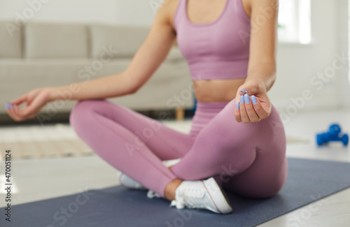 Calm serene relaxed woman practicing yoga and meditation at home, reaching zen and enjoying inner peace. Cropped indoor shot of unrecognizable beautiful young lady sitting in crossed legged lotus pose
