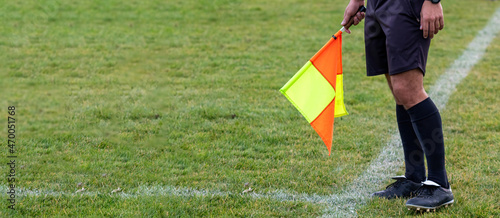 Football soccer arbiter assistant with flag at hands. Blurred green field background