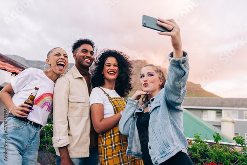 Happy friends taking a group selfie outdoors