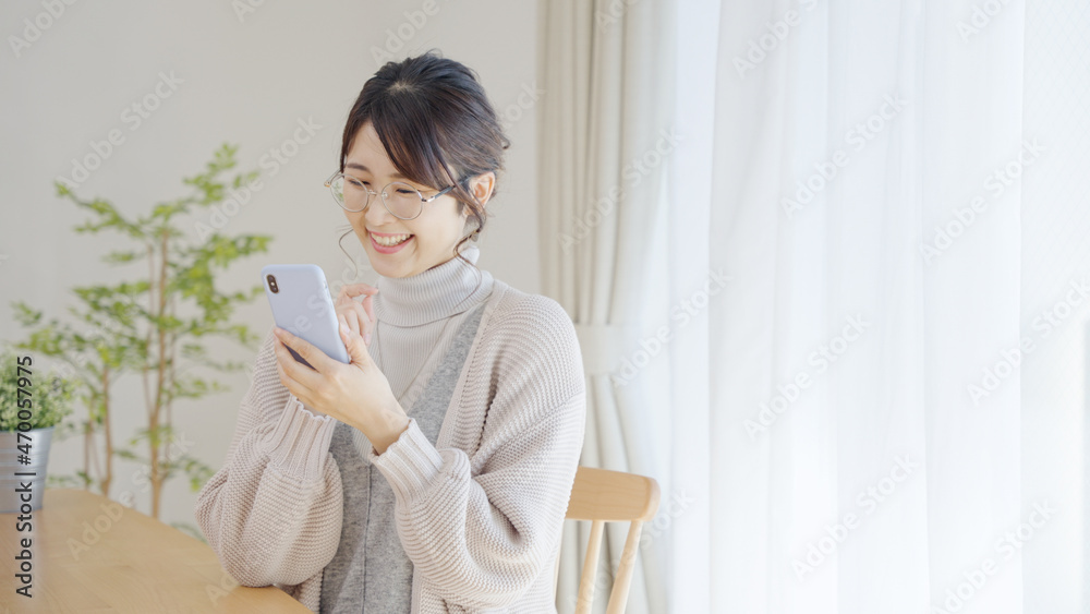 家でスマホを使う冬服のミドル女性