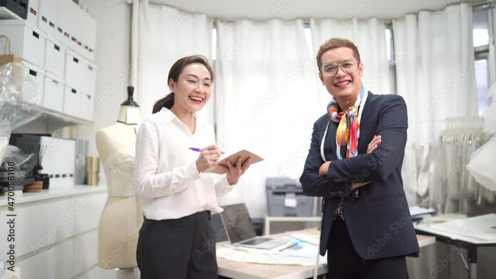 4K Portrait of Smiling Asian LGBTQ guy bridal shop owner working together with female assistant in office room at wedding studio. Small business entrepreneur wedding planner and designer concept 4K Portrait of Smiling Asian LGBTQ guy bridal shop owner working together with female assistant in office room at wedding studio. Small business entrepreneur wedding planner and designer concept