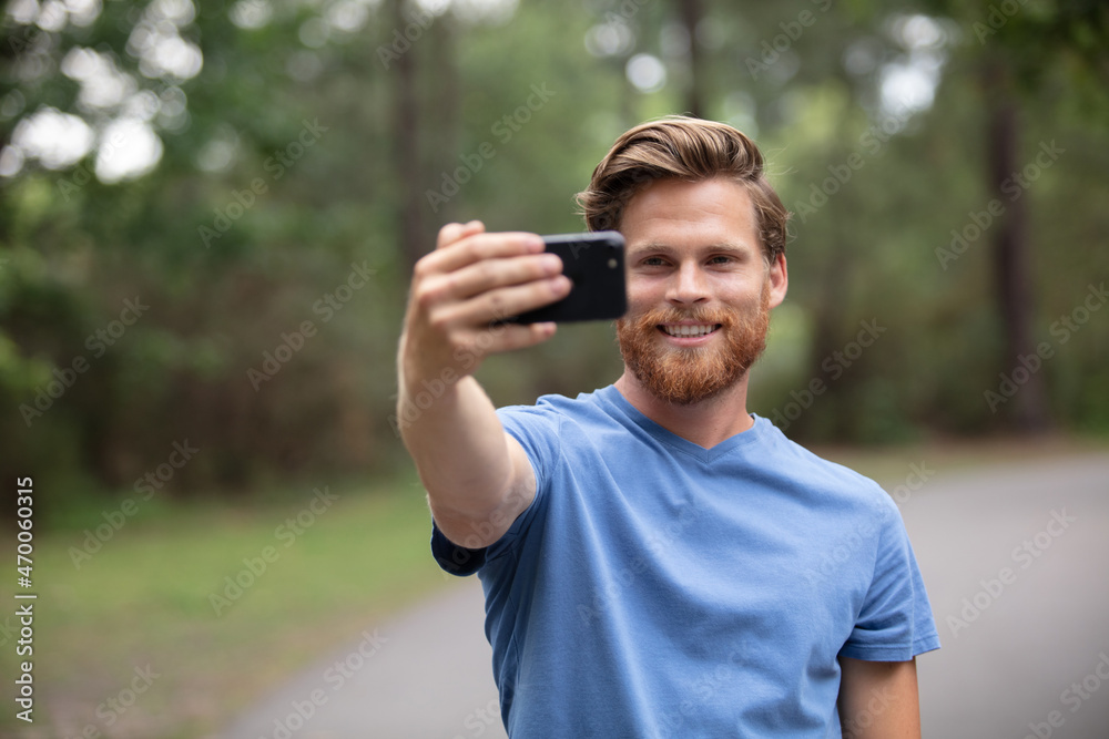 man sitting and makes selfie in forest