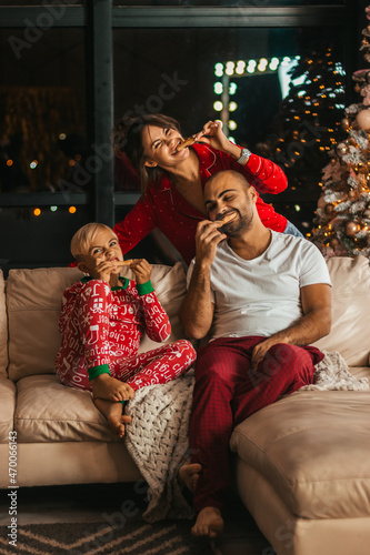 Happy family in Christmas pajamas eats pizza on the couch fun. Selective focus