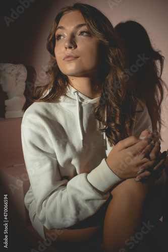 Young pretty woman in white sweater with curly hair opposite the lantern, on the pink background photo