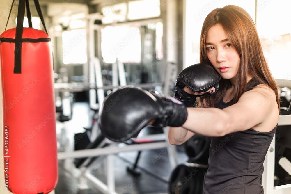 Portrait asia woman with black boxing gloves and red punching bag wearing sportswear in fitness or gym center, Strength sporty female and weight loss concept