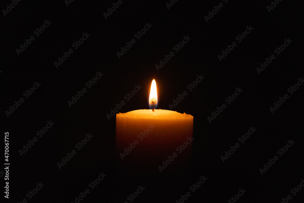 One single light candle burning brightly in the black background.Spiritual candle yellow flame. Flame of candle in the darkness.Copy space. One single light candle burning brightly in the black background.Spiritual candle yellow flame. Flame of candle in the darkness.Copy space.