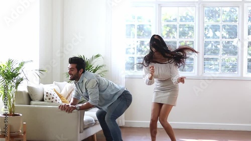 Portrait of joyful couple laughing and dancing while having fun at home together. photo