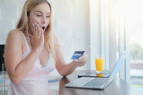 caucasian woman playing laptop with credit card in morning