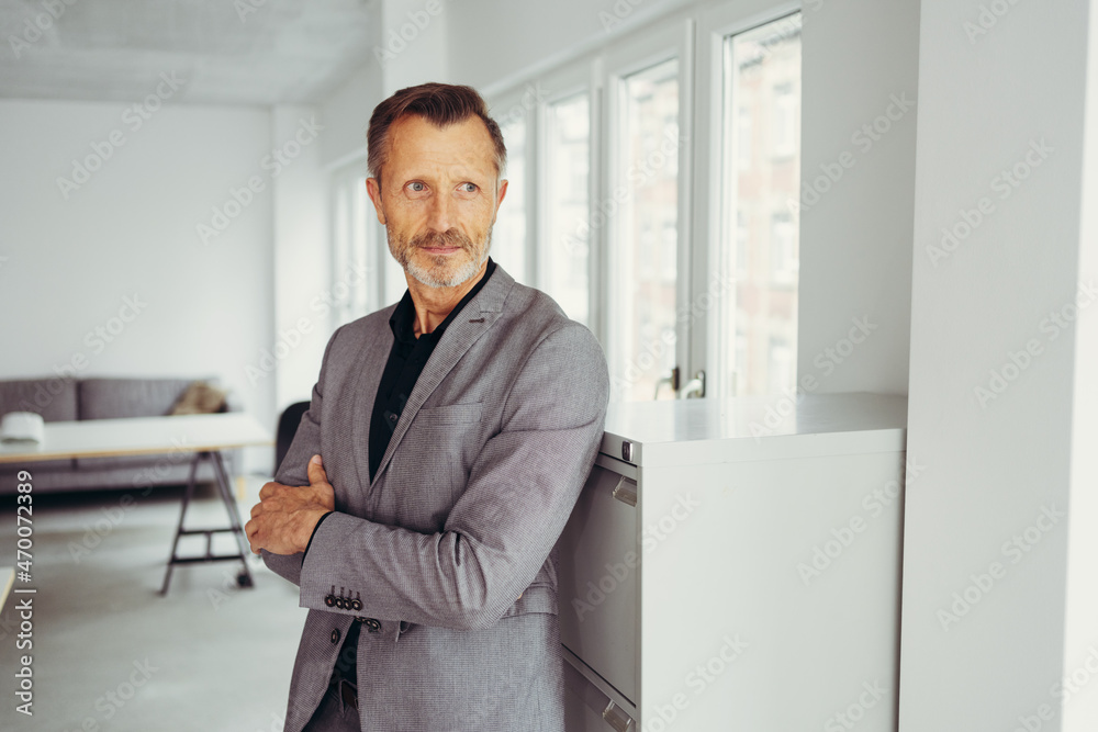 Troubled businessman standing deep in thought with folded arms Troubled businessman standing deep in thought with folded arms