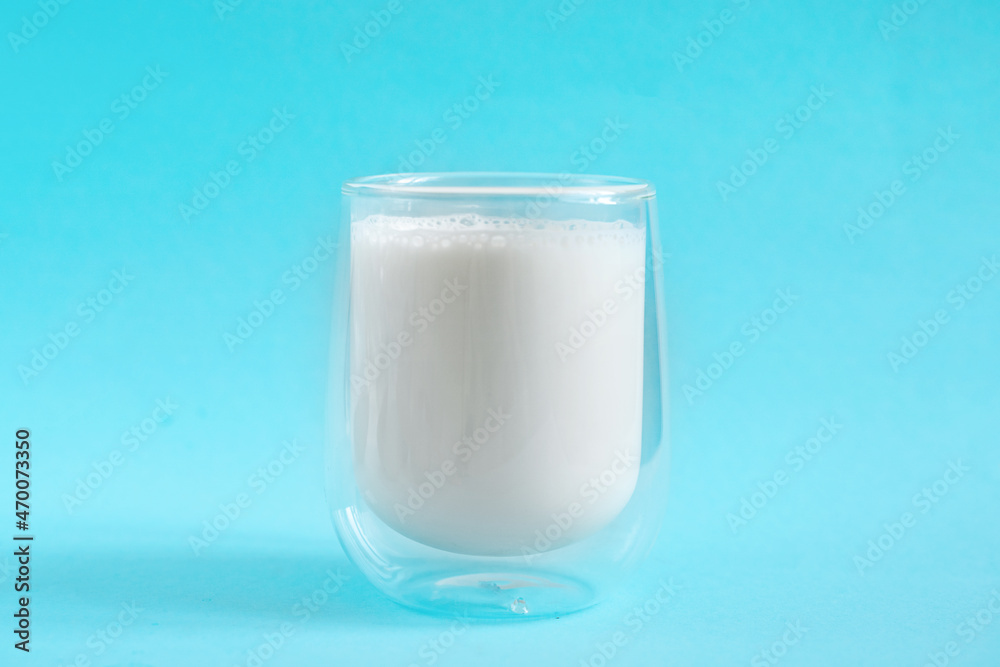 Milk in double glass insulate glass on blue minimal background. Lactose free milk made of vegan ingredients. Source of calcium Milk in double glass insulate glass on blue minimal background. Lactose free milk made of vegan ingredients. Source of calcium