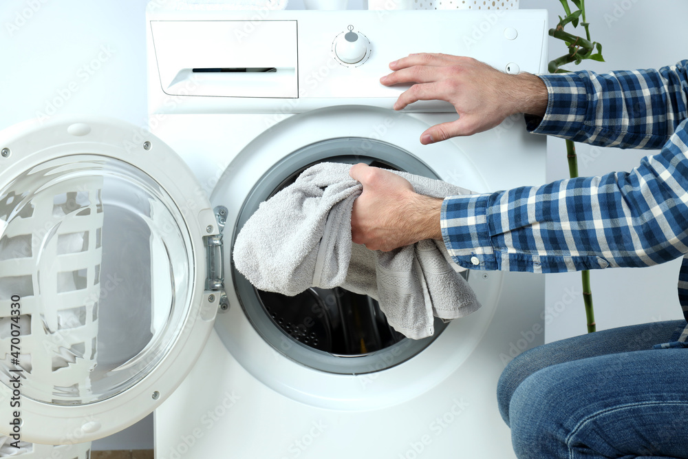 Concept of housework with washing machine and guy on white background Concept of housework with washing machine and guy on white background