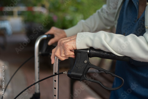 Old person's hands holds at handles modern comfortable walker. Difficult for elderly human to walk without support. Lifestyle of old person. Close-up. Safety for life.