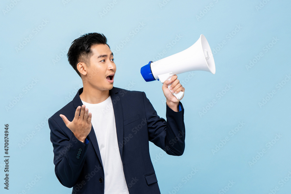 Young handsome Asian man with megaphone in isolated light blue color background Young handsome Asian man with megaphone in isolated light blue color background