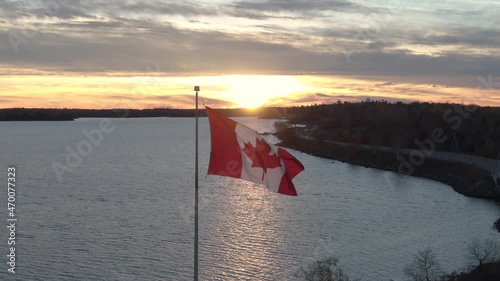 aerial push past Canadian Flag flying during sunset over water. photo