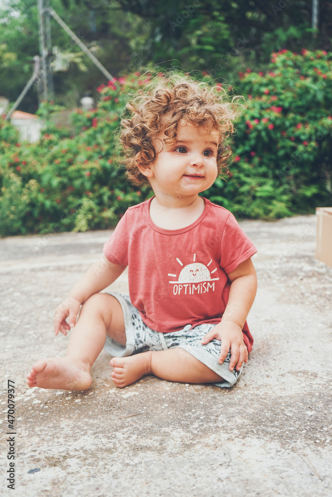 Fototapeta premium Cute toddler sit on the backyard floor