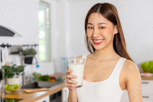 Young Asian Thai woman holding glass of milk and drinking
