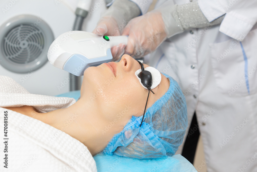 Woman client in a beauty salon is undergoing a photo rejuvenation procedure of alignment skin tone, removing traces of pigmentation. Starting the rejuvenation process by producing own collagen