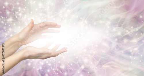 Healing Energy Lightworker Healing Hands and white light message banner - female hands with white light between against a pale pink ethereal shimmering background with copy space