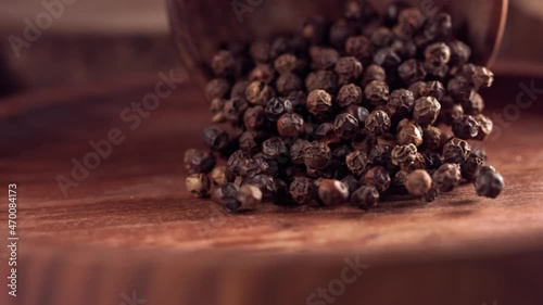 Black pepper falling on a wooden table .Slow motion. Close up photo