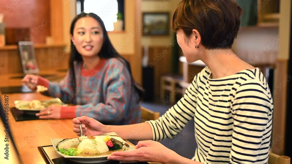 友人とカウンター席で食事をする女性たち