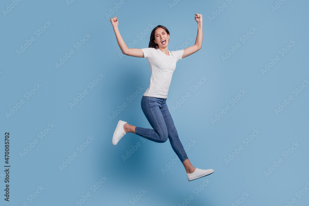 Portrait of funky girlish active lady jump run raise fists scream goal on blue background