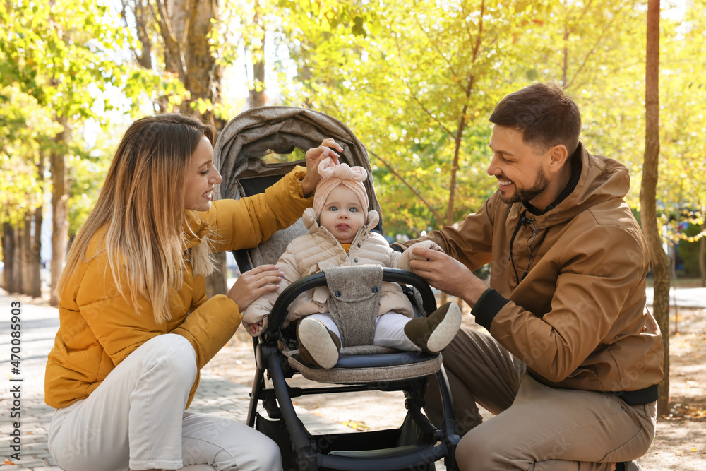Happy parents with their baby in stroller at park on sunny day Happy parents with their baby in stroller at park on sunny day