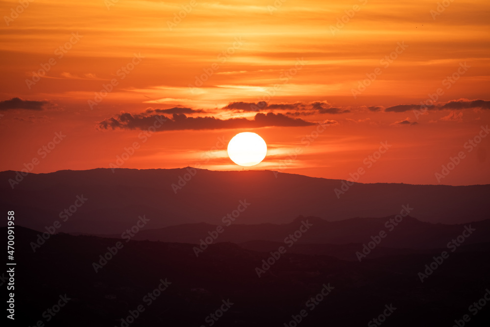 Fototapeta premium Beautiful orange sunset. Sunset in Sardinia. Red sky over hills. Aurora effect. 