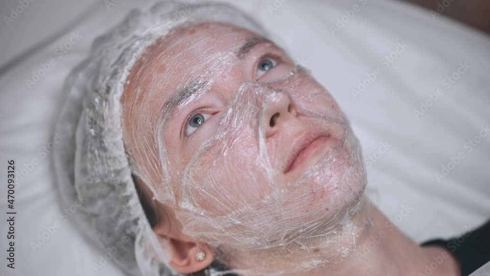 The girl lies in a plastic wrap. Hydrogenation process of the facial skin. The girl lies in a plastic wrap. Hydrogenation process of the facial skin.