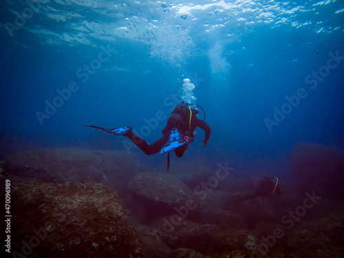 Scuba diver from behind. Diving in clear water. Rocks underwater. Underwater diving. Sardinia diving