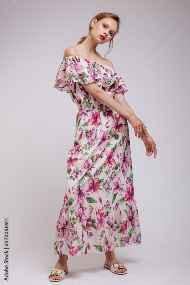 High fashion photo of a beautiful elegant young woman in pretty long dress with floral patterns in red color posing over white, soft gray background. Slim figure. Studio Shot. Femininity, tenderness High fashion photo of a beautiful elegant young woman in pretty long dress with floral patterns in red color posing over white, soft gray background. Slim figure. Studio Shot. Femininity, tenderness