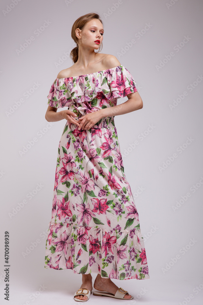 High fashion photo of a beautiful elegant young woman in pretty long dress with floral patterns in red color posing over white, soft gray background. Slim figure. Studio Shot. Femininity, tenderness High fashion photo of a beautiful elegant young woman in pretty long dress with floral patterns in red color posing over white, soft gray background. Slim figure. Studio Shot. Femininity, tenderness