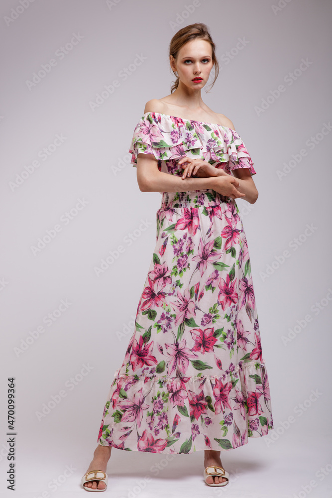 High fashion photo of a beautiful elegant young woman in pretty long dress with floral patterns in red color posing over white, soft gray background. Slim figure. Studio Shot. Femininity, tenderness High fashion photo of a beautiful elegant young woman in pretty long dress with floral patterns in red color posing over white, soft gray background. Slim figure. Studio Shot. Femininity, tenderness
