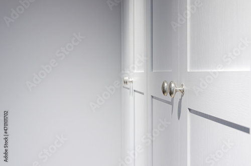 Minimal white closet or wardrobe with silver door handles. Close-up and selective focus at the knob handle.