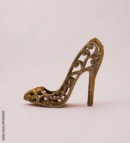 Christmas or New Year decoration - female golden high-heeled shoes over white background.