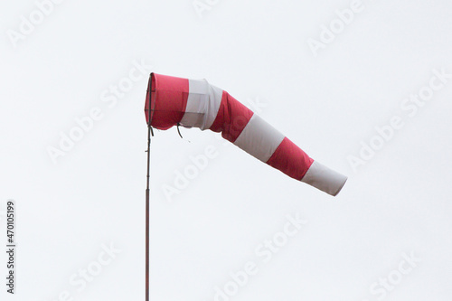 Red and white weather vane on a cloudy background