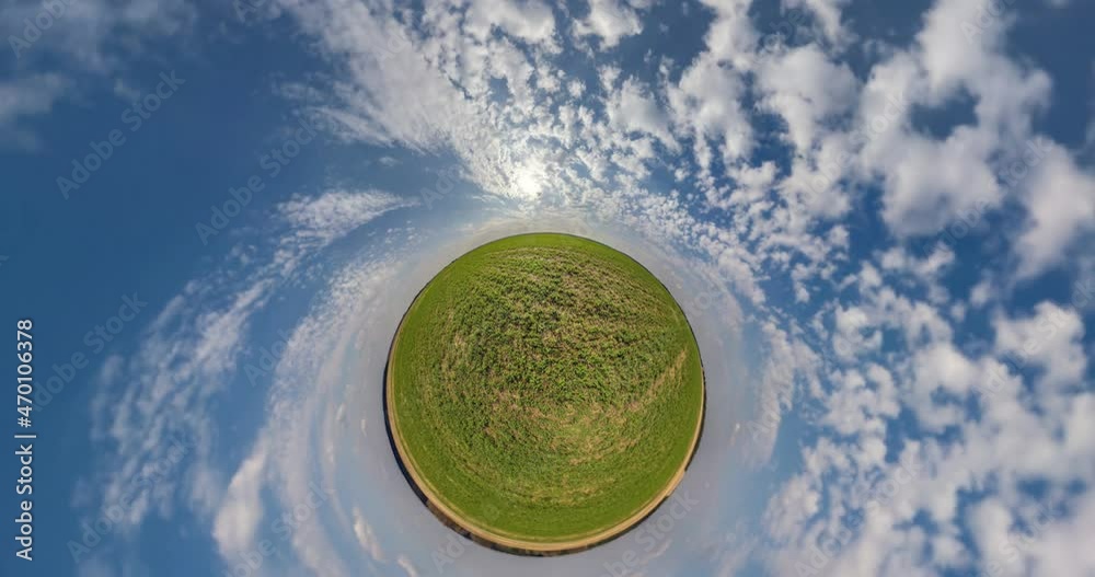 abstract spiral rotation of green sphere spins inside blue sky with clouds. Little planet loop rotate. 