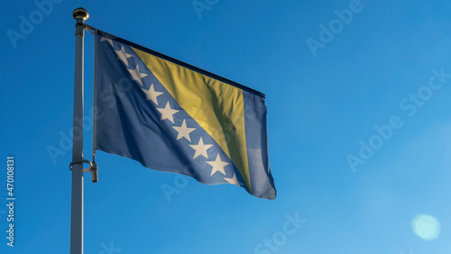 Bosnia Herzegovina national flag waving in the wind on a deep blue sky. Diplomacy and international relations concept.