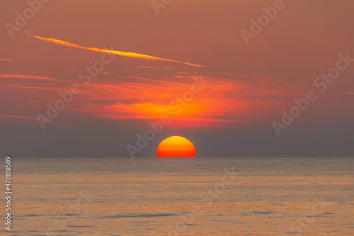 The sun's disk sets over the sea horizon.