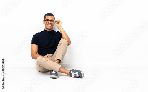 African American man sitting on the floor with glasses and happy
