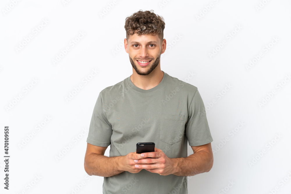 Young caucasian handsome man isolated on white background sending a message with the mobile Young caucasian handsome man isolated on white background sending a message with the mobile