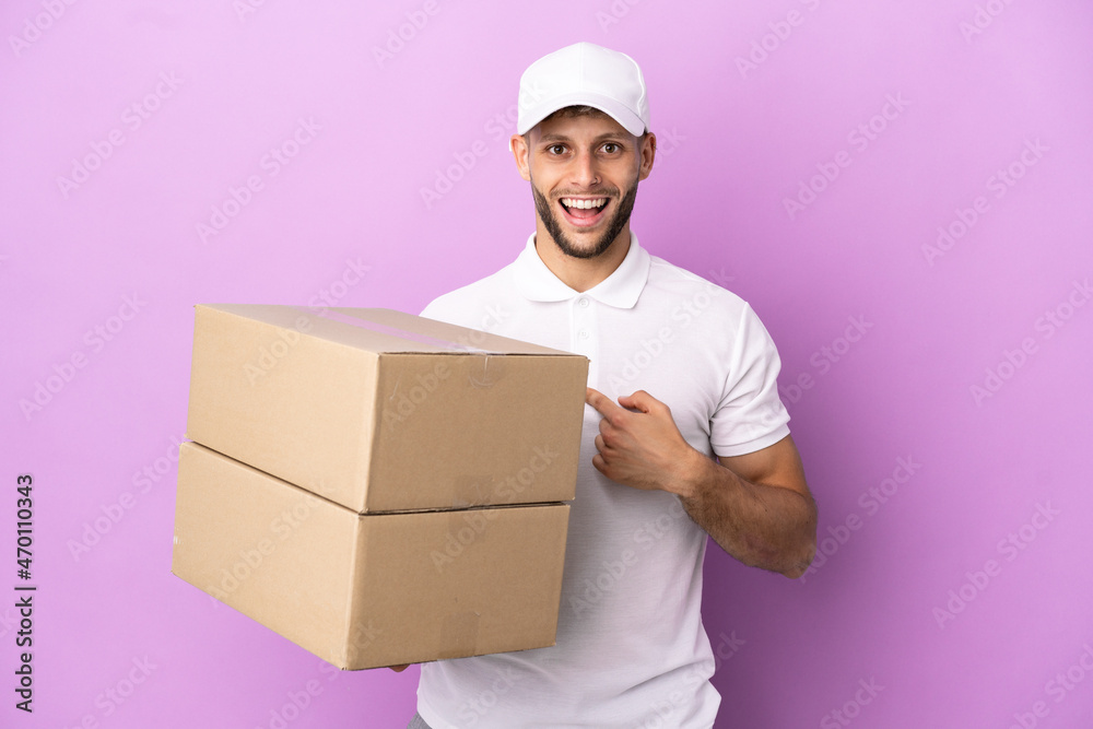 Delivery caucasian man isolated on purple background with surprise facial expression Delivery caucasian man isolated on purple background with surprise facial expression