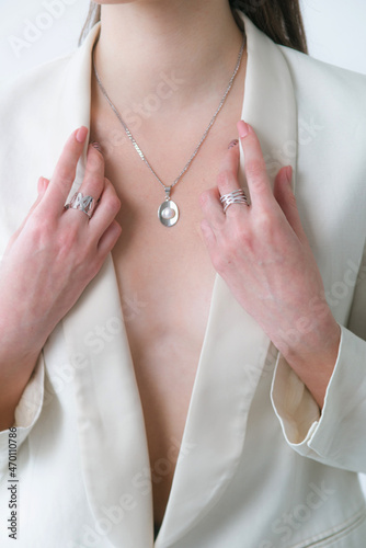 Trending silver necklace with pearls on a beautiful young girl in a white fashionable jacket. Beauty and fashion 
