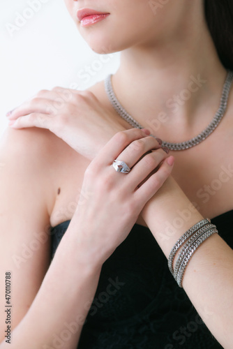 Trendy silver earrings bracelet and ring on a beautiful young girl with long dark hair. Beauty and fashion 