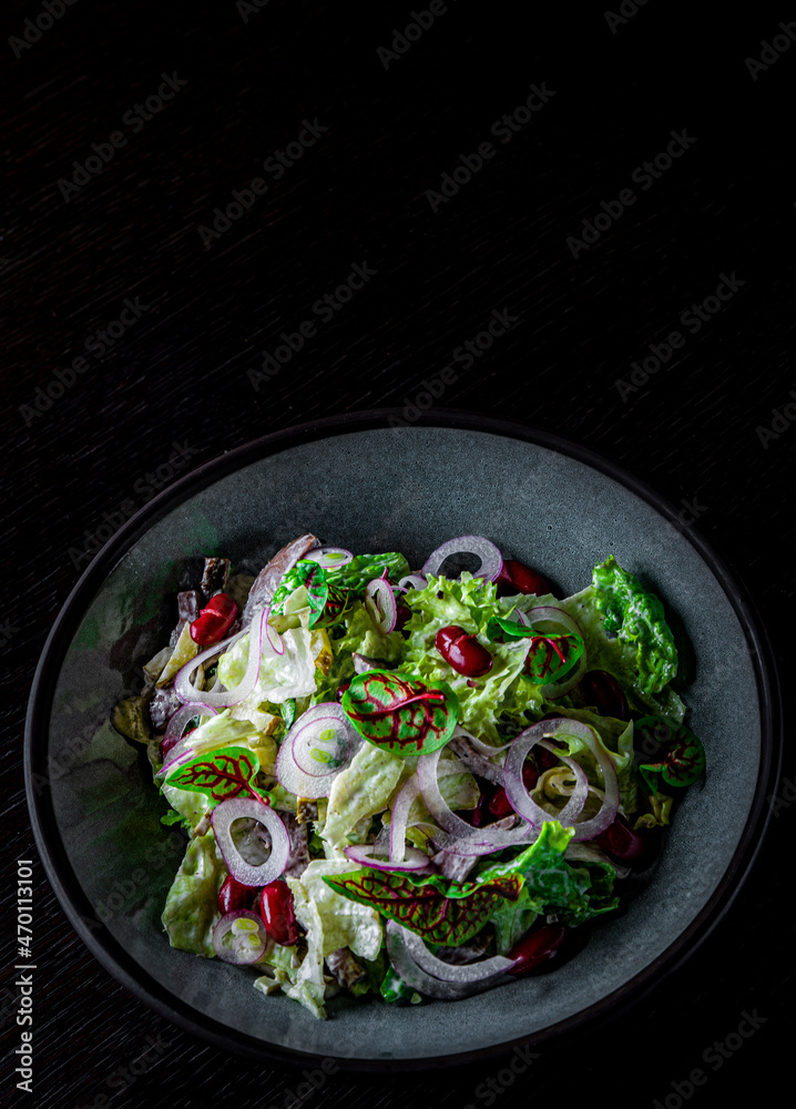 Mediterranean red beans salad with mix of lettuce leaves and onion on black bowl Mediterranean red beans salad with mix of lettuce leaves and onion on black bowl