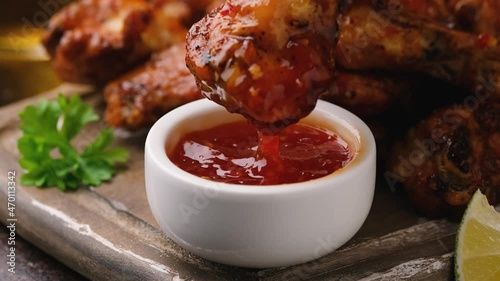 Dipping buffalo chicken wings in sweet chili sauce. fast food.