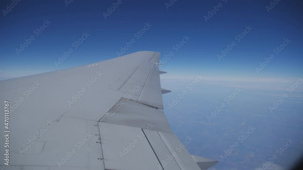 The view from the window of the plane on the wing hovering against the blue sky. Flying by plane. The view from the window of the plane on the wing hovering against the blue sky. Flying by plane.